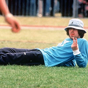 Liam Gallagherod pop group Oasis gives the v sign as hlies on the grass during a friendly
