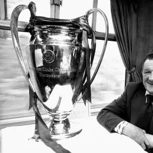 Liverpool manager Bob Paisley withthe European Cup trophy sitting on a train following