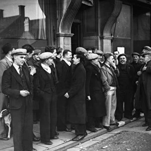 Men queuing up outside the Labour Exchange to collect their money. 29th May 1945