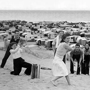 Men and women play a game of cricket on the sand beach. Holidays in Britain