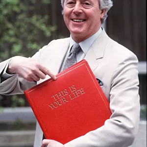 Michael Aspel TV Presenter of this is your life holding red book