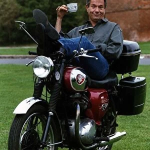 Michael Elphick actor sitting on motorbike holding cup of tea