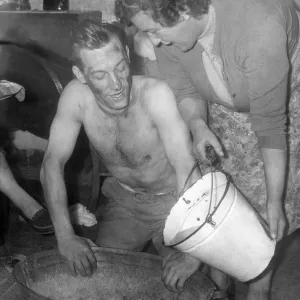 Un minero, el señor Allan Hedley, se lava en una bañera de latón con agua hervida sobre la única fogata. Un minero, el señor Allan Hedley, se lava en una bañera de latón con agua hervida sobre la única fogata.