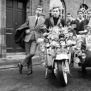 Les mods portant des costumes et des parkas sur des scooters motorisés recouverts de lampes supplémentaires. Les mods portant des costumes et des parkas sur des scooters motorisés recouverts de lampes supplémentaires.