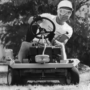 Stirling Moss sentado en cortacésped llevando casco de choque. Stirling Moss sentado en cortacésped llevando casco de choque.
