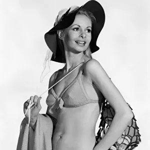 Model wearing a bikini. and hat, carrying a bag over her shoulder August 1970