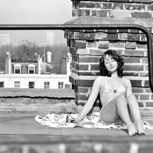 A model wearing a bikini as she subathes on a rooftop on Kings Road in Chelsea, London