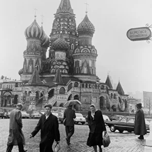 Moscovites with their heads down against the rain seen here passing St Basil