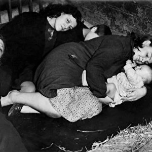 A Mother protects her baby whilst taking cover from air raid in a farmers barn