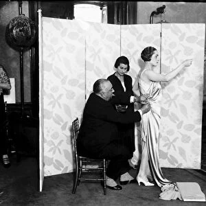 Paul Poiret pinning a gown on one of his Models