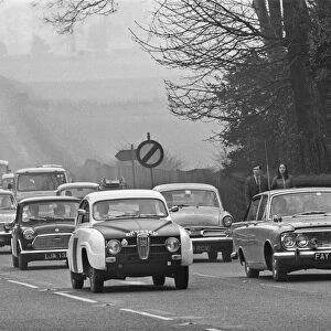 Pedestrians look over at the traffic built up along the A556 towards Manchester