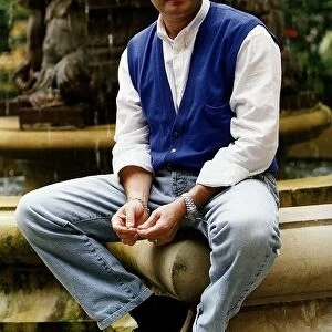 Phil Collins singer poses for a picture while sitting on the edge of a water fountain