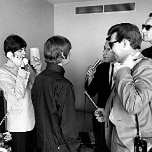 Ringo Starr talks to reporters and Paul McCartney talks on the phone August 1964 at