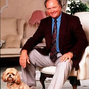 Ron Atkinson Football manager sitting on chair at home with his pet dog. January 1991