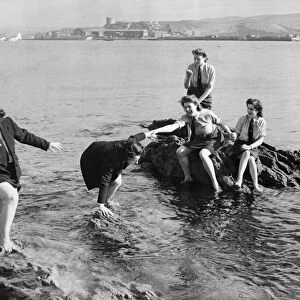 Service girls caught on the rocks in Plymouth, Devon. The US soldiers nearby