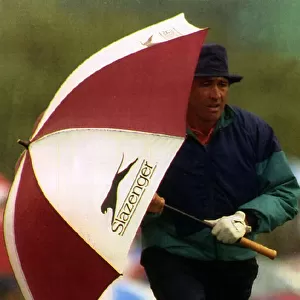 Seve Ballesteros holding a golf umbrella at his side whilst walking to the next hole