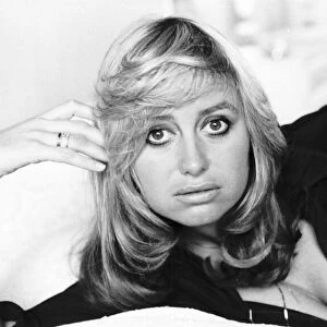 Susan George actress lying on a bed on her side holding her head up with her fingers