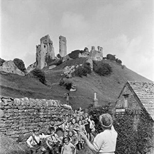 A woman guides a group of children in front of Corfe Castle in Dorset, July 1947