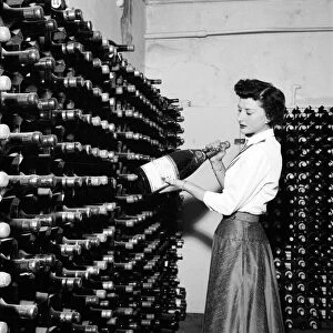 Woman seen here inspecting wine bottles. 1957 A17-001