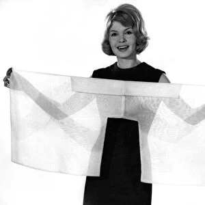 Woman wearing a clack sleeveless dress holding a see through scarf