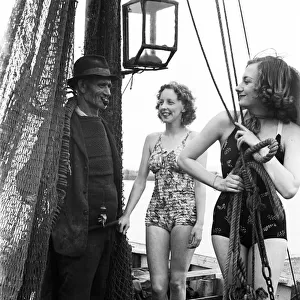 Women in their bathing costumes with a fisherman, along the coast, Hastings, circa 1945