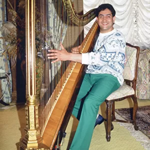World snooker champion Joe Johnson poses playing a harp. 28th May 1986