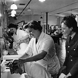 World War II Women. W. A. A. F. hairdresser seen here shampooing (washing) new recruits hair