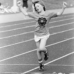 A young boy raises his arms in celebration as he crosses the finish line to win the race