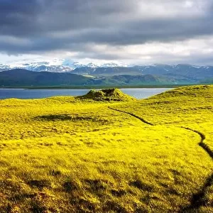 Gorgeous Iceland landscape with green grass field, blue lake and snow-capped mountains in the background. Iceland, Europe