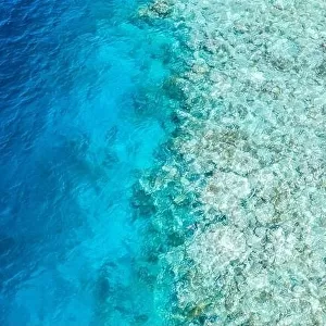Top view from drone at ocean, azure water and relax blue sea. Vacation and adventure. Turquoise water coral reef texture, shallow and deep ocean