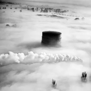 Prints of HITCHIN, Hertfordshire, 1949. Aerial view. A gasometer and the tips of trees rise up through the fog, as well as steam from a railway train passing the gasworks. Aerofilms Collection (see Links) Industry and Agriculture in England - Factories, Farming and Production: Hitchin Gasometer Print, Aerial View 1949
