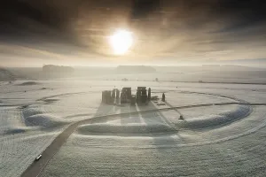Prints of Stonehenge, Amesbury, Wiltshire. Stonehenge Landscape. General view of the stone circle showing circular ditch with inner and outer bank at sunrise. View from north west Explore South West England: Coast, Countryside and Travel: Stonehenge Print at Sunrise