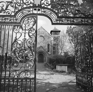 Prints of ST PANCRAS OLD CHURCH, Camden Town, London. A view through the wrought iron gateway leading into St Pancras Gardens. Photograph by John Gay. Date range: 1960-1972 Iconic Photographers of England - Historic Image Collections: St Pancras Old Church Print - Wrought iron gateway view