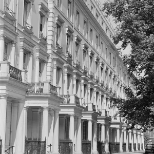 Prints of A terrace of four-storey houses decorated in the neo-classical style, including projecting porches with columns and balconies above them, probably in Kensington Victoriana Prints: Print of a Neo-Classical Terraced House Row