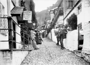 Prints of High Street, Clovelly, Devon. Looking up the cobbled main street in Clovelly, showing the New Inn on the north side of the street, with people leaning against the walls of the buildings Historic Images 1920s To 1940s Prints: Clovelly High Street Print, 1880s