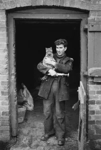 Prints of HENLEY MILL, HENLEY, BITTERLEY, SHROPSHIRE. A miller holding a cat outside Henley Mill, 1960s Industry and Agriculture in England - Factories, Farming and Production: Henley Mill Print: A miller with a cat in the 1960s