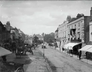 Prints of Looking down the street with stationary carts and wagons outside the Spread Eagle public house. The Essex Arms and SPQR Stores stand opposite. Watford, Hertfordshire. Photographer: Henry William Taunt Towns and Cities of England - Streets, Skylines and Urban Life: Print of Market Place, Watford