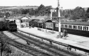 Prints of A view of Brent station, Devon, c.1950s, showing a locomotive at the station and members of station staff on the platform Stations And Halt Prints: Brent Station Print, Devon c.1950s - Locomotive and Staff