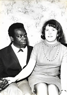 Black man and white woman sitting on a bed holding hands Black man and white woman sitting on a bed holding hands