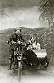 Boy & girl on a 1922 Royal Enfield motorcycle & sidecar in a Boy & girl on a 1922 Royal Enfield motorcycle & sidecar in a