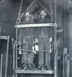Prints of Several coal miners with blackened faces stand in the shaft lift at the end of their shift in a coal mine in South Wales Industrial Prints: Coal Miners in Shaft Lift Print, South Wales