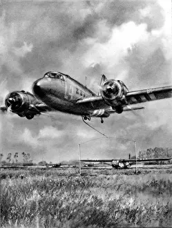 Prints of Illustration showing a Douglas Dakota, C-47 Skytrain, swooping down with a hook trailing to pick up a Waco glider, Normandy, France, 1944 Airplanes And Aviation Prints: Douglas Dakota Picks Up Glider, Normandy Print