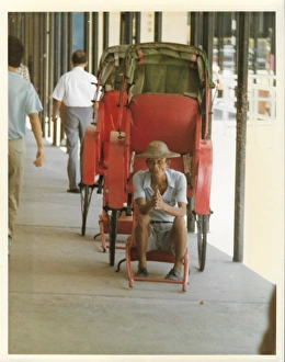Elderly Chinese man in an empty red rickshaw Elderly Chinese man in an empty red rickshaw