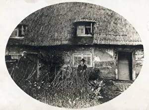 Elderly couple standing proudly outside their thatched English country cottage Elderly couple standing proudly outside their thatched English country cottage
