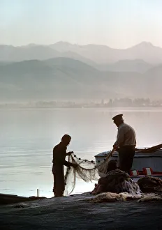 Two fishermen sort their nets on stone quayside - Fetheye Two fishermen sort their nets on stone quayside - Fetheye