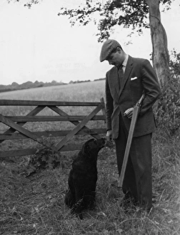 Gamekeeper and dog standing near five-bar gate Gamekeeper and dog standing near five-bar gate