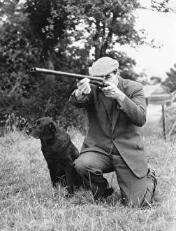 Gamekeeper taking aim, his dog at his side Gamekeeper taking aim, his dog at his side