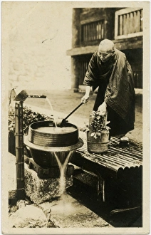 A Japanese man watering his flowers from a water pump A Japanese man watering his flowers from a water pump