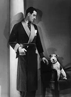 Prints of Man models a wool jersey dressing gown, and his wire- haired fox terrier poses for the camera Fox Terrier Wire Prints: Man in Dressing Gown Print: A Man and His Fox Terrier