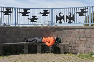 A man sleeps on a bench on Morecambe promenade A man sleeps on a bench on Morecambe promenade
